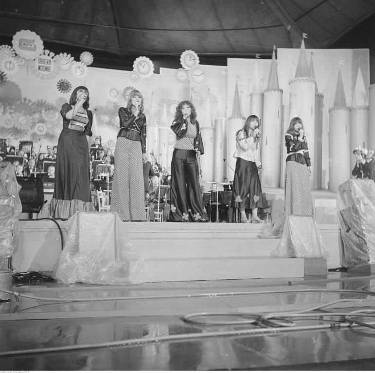 pięć kobiet śpiewa na scenie, w tle orkiestra